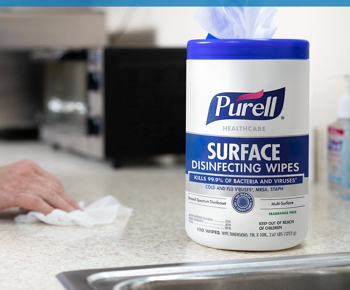 Hand pulling a PURELL surface disinfecting wipe from a canister on a kitchen counter